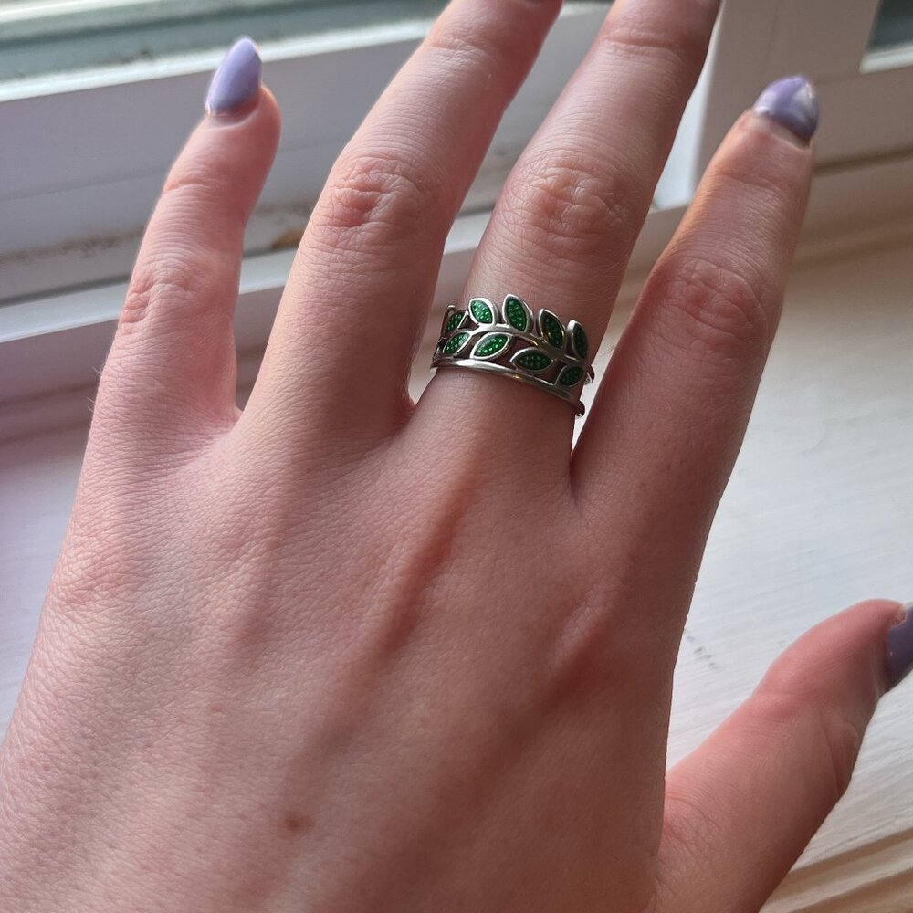 Intricate green leaves wrap around silver ring